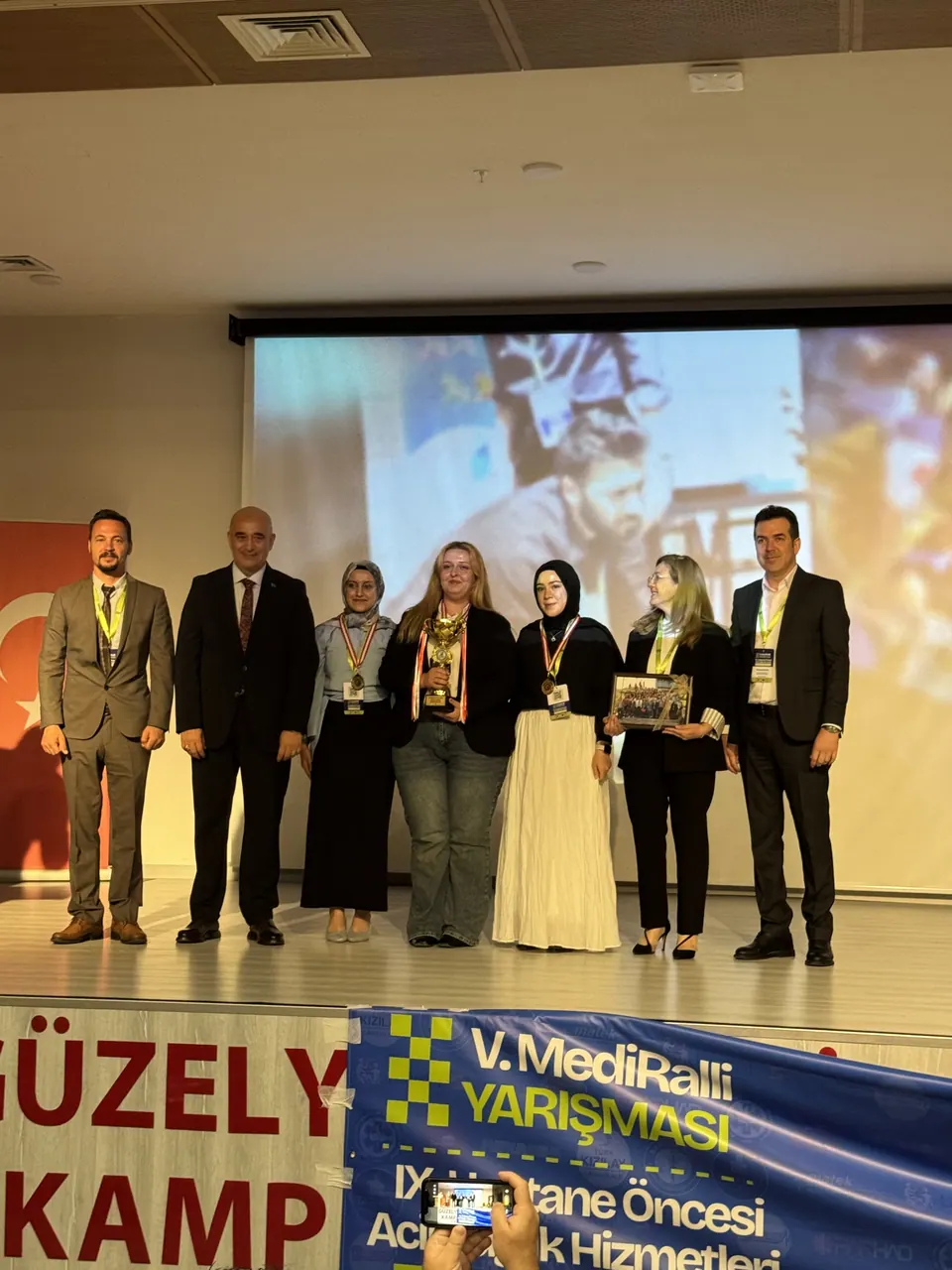 Sahnede plaketleriyle poz verenler