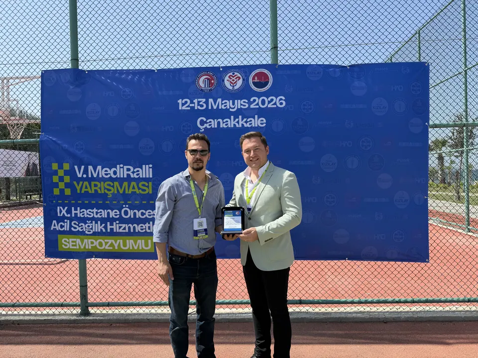 MediRalli panosu önünde plaket tutan iki kişi