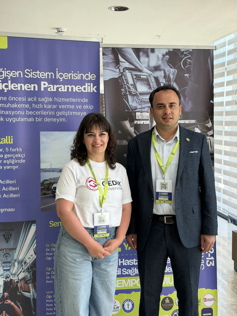 Roll-up önünde poz veren iki kişi